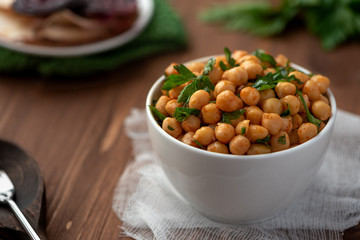 Cooked chickpeas with parsley and paprika in a white bowl. Vegetarian food.