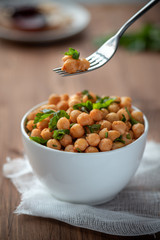Cooked chickpeas with parsley and paprika in a white bowl. Vegetarian food.