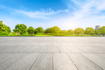 Empty square floor and green trees under blue sky