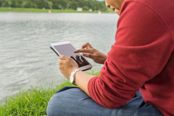Man sitting in the park, using tablet to surf
