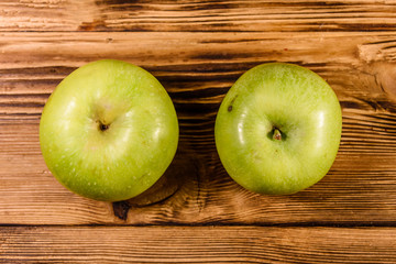 Two ripe green apples on a wooden table. Top view