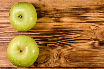 Two ripe green apples on a wooden table. Top view
