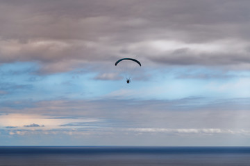 Scene of paraglider over the sea against cloudy blue sky at sunset
