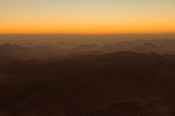 Beautiful golden sunrise in the mountains. The first appearance of the sun. Amazing view from Mount Sinai (Mount Horeb, Gabal Musa, Moses Mount). Sinai Peninsula of Egypt