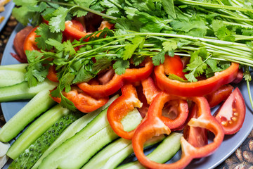 Cut cucumbers and tomatoes pepper parsley on table