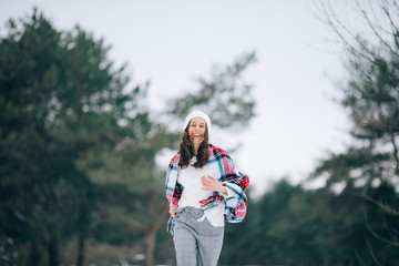 Young woman has a fun and laughs in the winter pine forest.