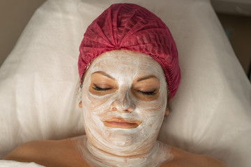 Spa concept. Young woman with nourishing mask on face relaxing in spa salon