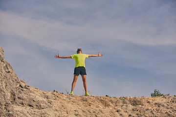 Man celebrating success after good training / exercise on the top of a hill.