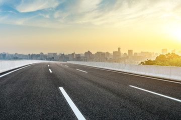 Panoramic city skyline and buildings with empty asphalt road at sunrise