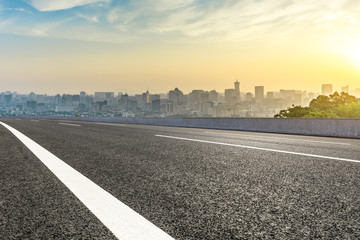 Panoramic city skyline and buildings with empty asphalt road at sunrise
