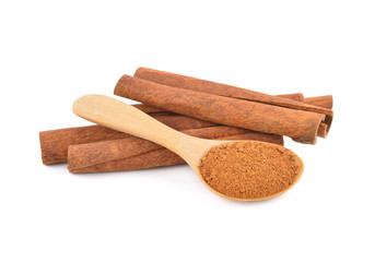 dried ground cinnamon in wooden spoon and cinnamon stick on white background
