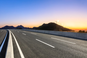 Empty asphalt road and mountains at beautiful sunset