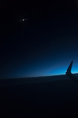 Airplane flying high in the sky at night, blue sky and dark blue clouds at dark night