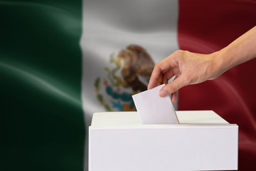 Close-up of human hand casting and inserting a vote and choosing and making a decision what he...