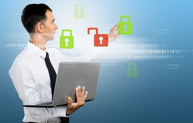 Businessman holding laptop and touching icons on background