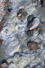 Water filled with mineral salts, flows impetuously among the stones of a stream on the slopes of Mount Rosa in Piedmont, Italy