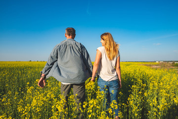 Romantic couple is walking through the field of yellow flowers