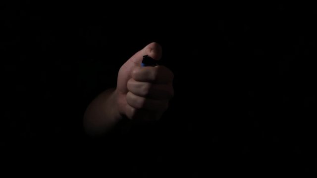 the hand appears from the dark and turns on the lighter and disappears.