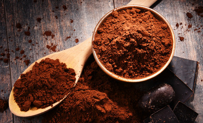 Composition with bowl of cocoa powder on wooden table