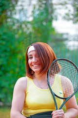 Disabled young woman on wheelchair playing tennis on tennis court.