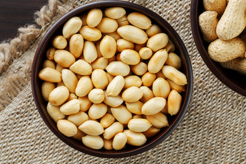 Peanuts in the shell and peeled close-up in cups. Roasted peanuts in their shells and peeled...