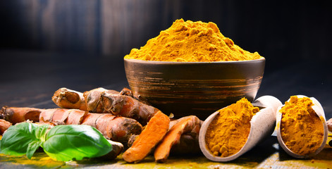 Composition with bowl of turmeric powder on wooden table © monticellllo