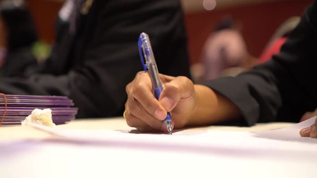 Document Report and Education Concept: Teacher woman hands holding pen for checking signing and note on white documents reports papers of paper files in meeting seminar room background.  