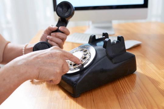 Aged woman using old phone when dialing telephone number