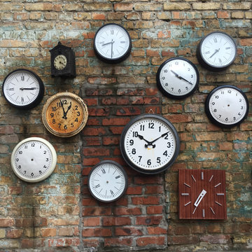 Many different clock on a brick wall. Time concept