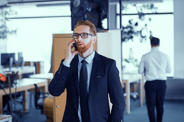 Office worker speaks by mobile phone in office