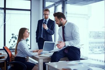Beautiful business people are studying documents, talking and smiling while working in office