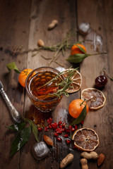 Fragrant fruit tea with tangerines, dried lemons and rosemary on a wooden table. Country style.