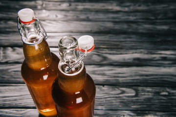 fermented tea in glass bottles on wooden table - obrazy, fototapety, plakaty