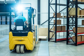 Warehouse equipment. Storage. The person works on a loader. Metal racks. Carton boxes. Forklift...