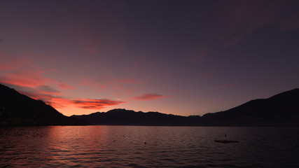 Tramonto sul lago, con nuvole rosse e rosa