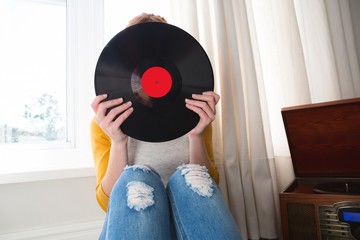 Woman hiding her face with vinyl record