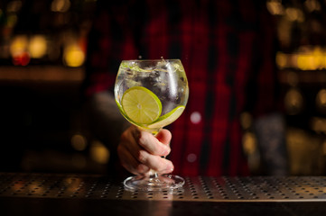 Barman holding a glass of fresh sour and sweet citrus cocktail