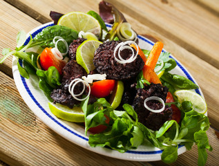 Prepared tasty blood sausage with  lettuce and lemon served at plate