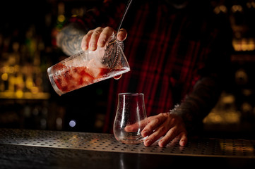 Barman pouring fresh and tasty cool bittersweet red cocktail