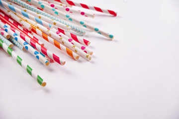 Drinking paper colorful straws for summer cocktails on white background with copy space. Top view.