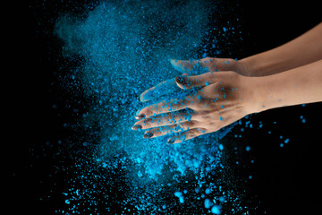 cropped view of adult woman holding blue holi powder and clapping on black background - obrazy, fototapety, plakaty