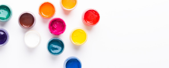 Multicolored gouache on a white background Isolated Paints in containers Top view Copy space Banner...