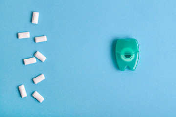 Dental floss and Chewing gum on a blue background. Space for text.