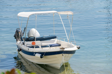 Small white blue motorized boat anchored on the shore