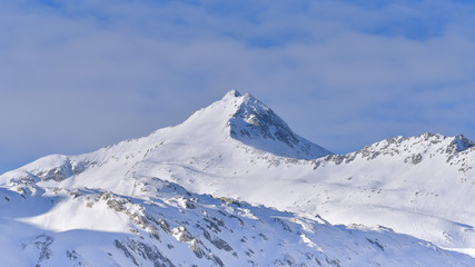 Fototapeta na wymiar Cima innevata della montagna, con nuvole dietro