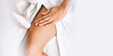 Body care. A young woman in the bathroom applies natural cream to her legs. Against varicose veins and leg edema Banner