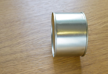 metal tin can lies on the end of a wooden table