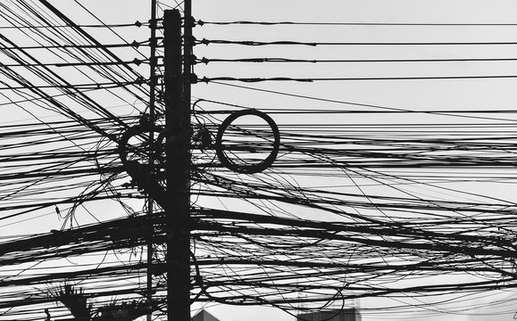 Electric pole with wires busy disorder found in place of disrepair in the city.This image is Siluett.