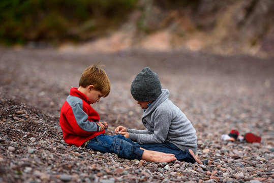 Two boys sitting on beach playing, United States