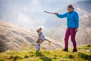 Fototapeta premium woman playing with her dog in beautiful mountain scenery in spring